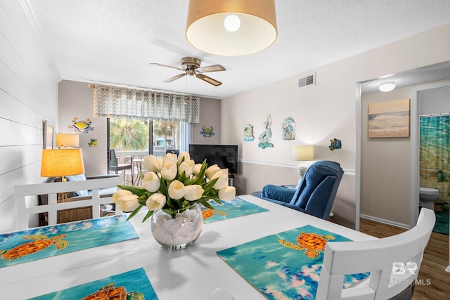 dining room with ceiling fan, visible vents, a textured ceiling, and wood finished floors