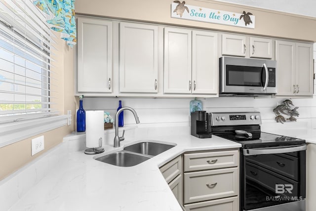 kitchen with sink, light stone countertops, and stainless steel appliances