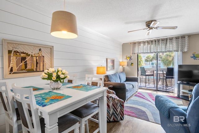 living area with a ceiling fan, crown molding, a textured ceiling, and wood finished floors