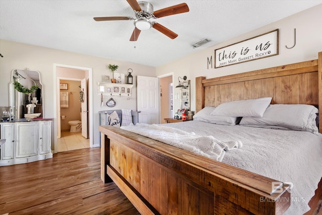 bedroom featuring a textured ceiling, ensuite bathroom, ceiling fan, and dark hardwood / wood-style floors