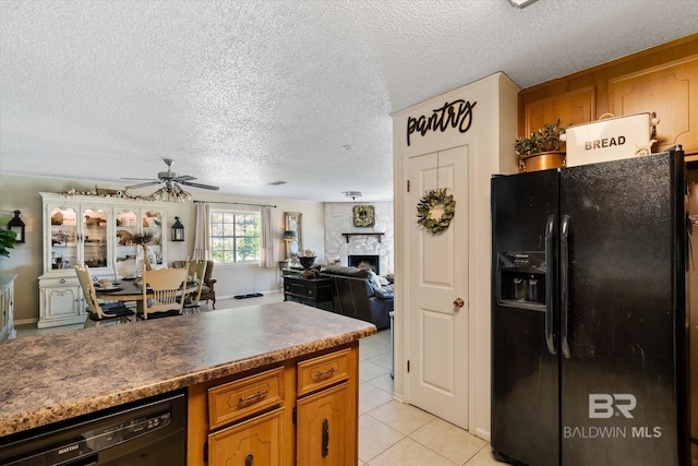 kitchen featuring black appliances, ceiling fan, a fireplace, a textured ceiling, and light tile patterned flooring