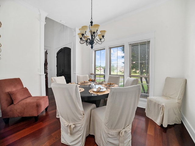 dining space with an inviting chandelier, crown molding, and dark wood-type flooring