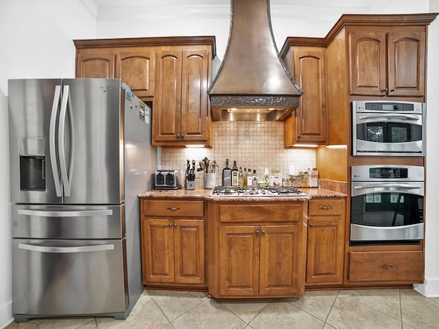 kitchen featuring tasteful backsplash, light tile patterned floors, light stone counters, stainless steel appliances, and custom range hood