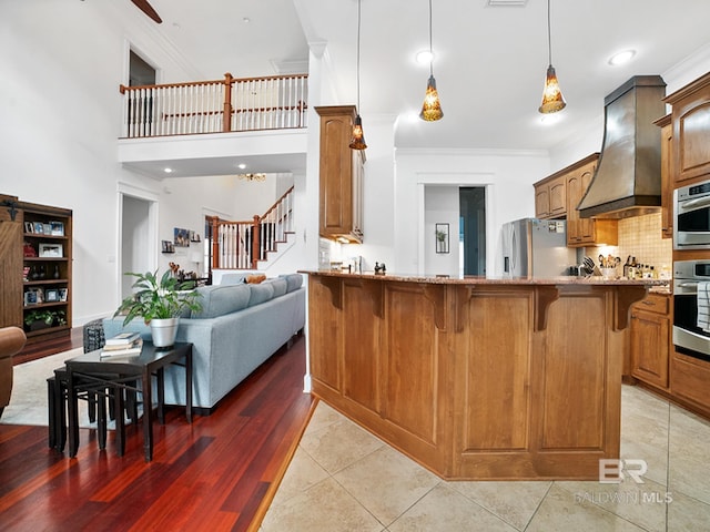 kitchen with premium range hood, tasteful backsplash, stainless steel fridge, ornamental molding, and kitchen peninsula