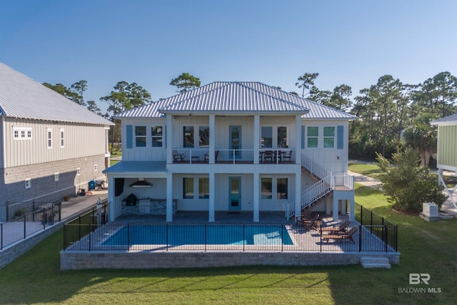 back of property with a yard, a patio, and a fenced in pool