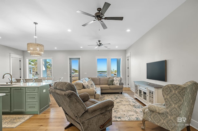 living room with light hardwood / wood-style floors, sink, and ceiling fan with notable chandelier