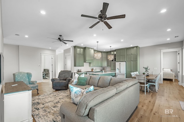 living room with sink, light hardwood / wood-style floors, and ceiling fan