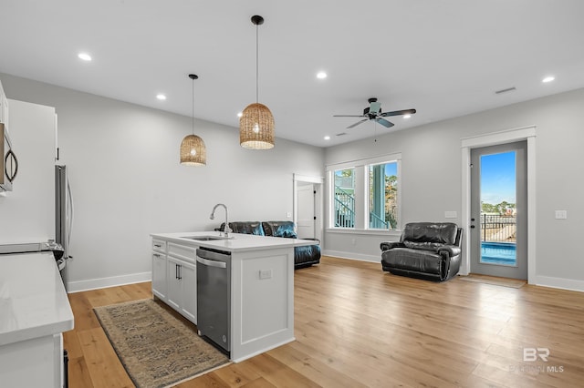 kitchen featuring stainless steel appliances, a center island with sink, sink, pendant lighting, and white cabinets