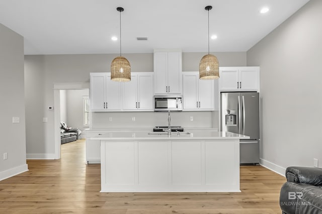 kitchen featuring appliances with stainless steel finishes, white cabinetry, a kitchen island with sink, and light hardwood / wood-style floors