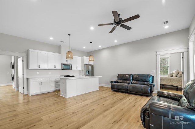 living room featuring sink, ceiling fan, and light hardwood / wood-style flooring