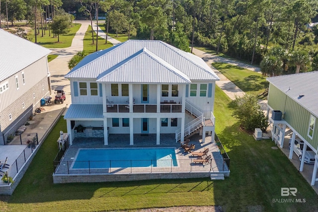 back of house with a fenced in pool, a patio area, a yard, and a balcony