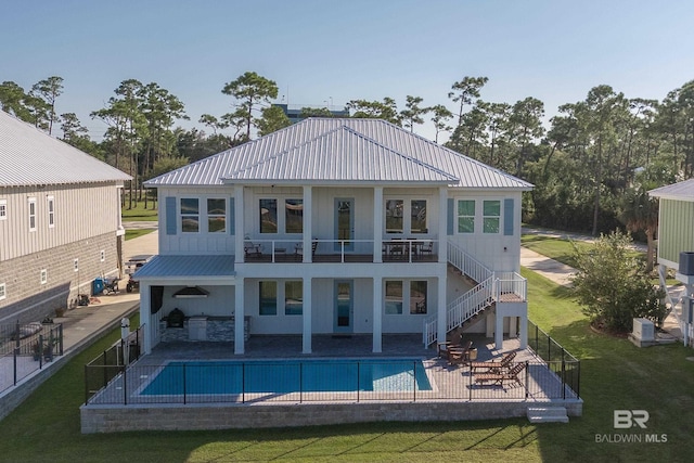 rear view of property with a lawn, a patio area, and a fenced in pool