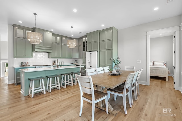 dining area featuring sink, light hardwood / wood-style flooring, and an inviting chandelier