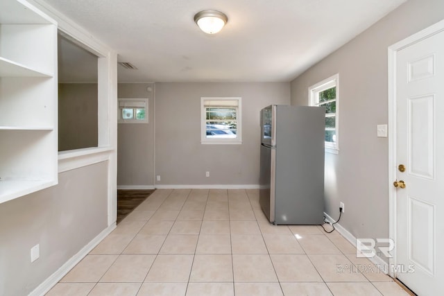 6451 S Barker Dr, Mobile, AL 36608 - kitchen featuring freestanding refrigerator, light tile patterned flooring, and baseboards