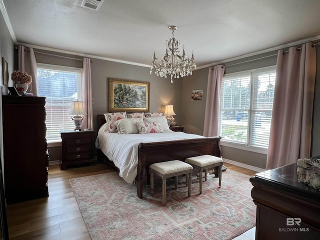 bedroom with light wood-type flooring, crown molding, and a notable chandelier