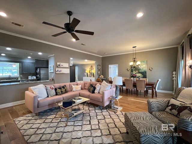 living room featuring ceiling fan with notable chandelier, light hardwood / wood-style floors, and ornamental molding