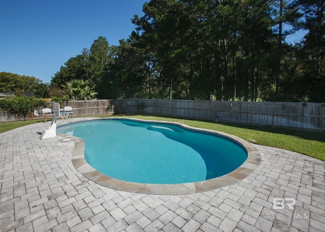 view of swimming pool featuring a fenced backyard, a fenced in pool, a lawn, and a patio area