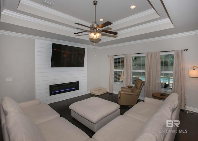living room with crown molding, ceiling fan, wood finished floors, and a raised ceiling