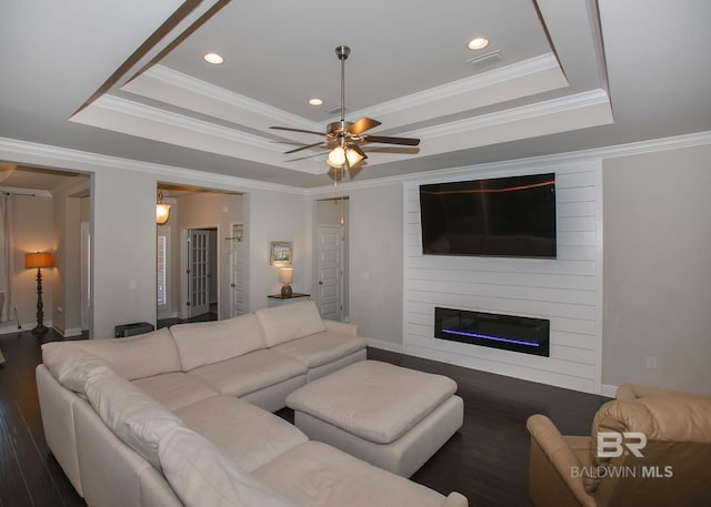 living room featuring a raised ceiling, a fireplace, a ceiling fan, and wood finished floors