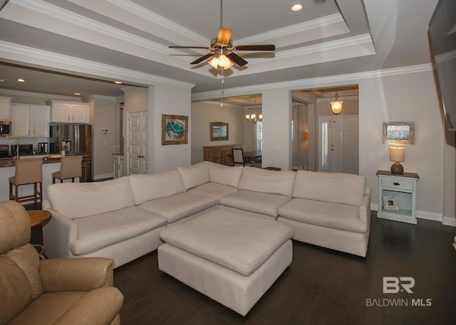 living area featuring a raised ceiling, baseboards, ceiling fan with notable chandelier, dark wood-style floors, and recessed lighting