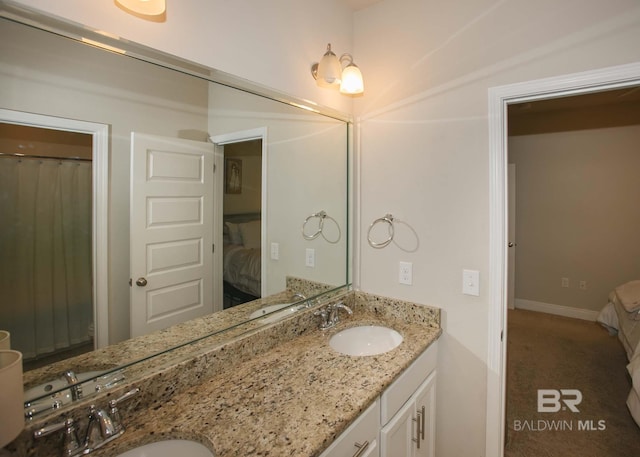 full bathroom with connected bathroom, double vanity, baseboards, and a sink