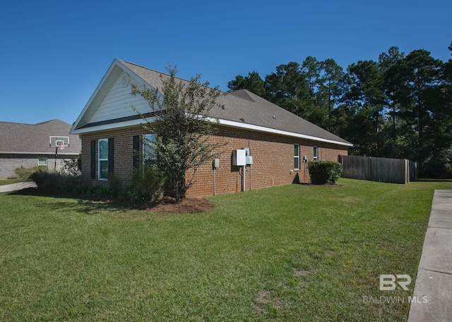 view of side of property featuring a lawn, brick siding, and fence