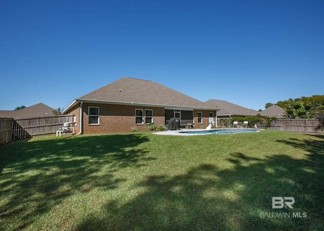 back of house featuring a lawn, brick siding, a fenced in pool, and a fenced backyard