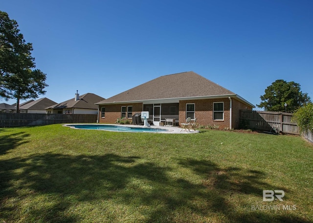 back of house with a fenced backyard, a fenced in pool, a lawn, and brick siding
