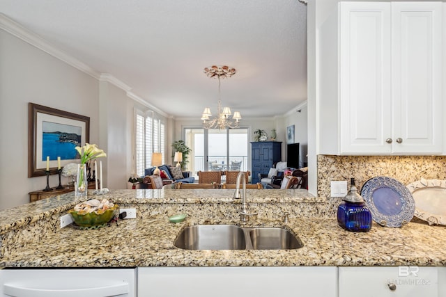 kitchen with ornamental molding, open floor plan, light stone counters, a chandelier, and a sink