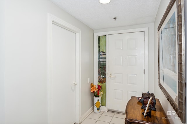 entryway featuring a textured ceiling, baseboards, and light tile patterned floors