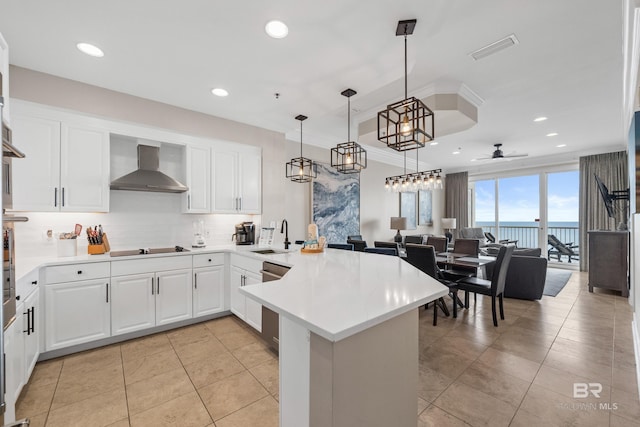 kitchen with a sink, backsplash, wall chimney range hood, a peninsula, and stainless steel dishwasher