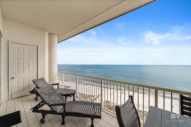 balcony with a water view and a view of the beach