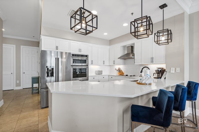 kitchen featuring backsplash, appliances with stainless steel finishes, a peninsula, wall chimney exhaust hood, and a sink