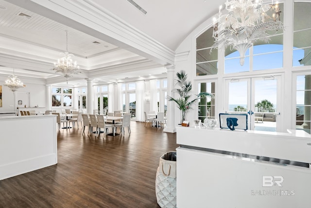 living area featuring plenty of natural light, decorative columns, dark wood-style flooring, and a chandelier