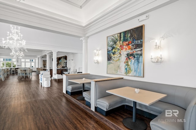 interior space with decorative columns, a notable chandelier, wood finished floors, and crown molding