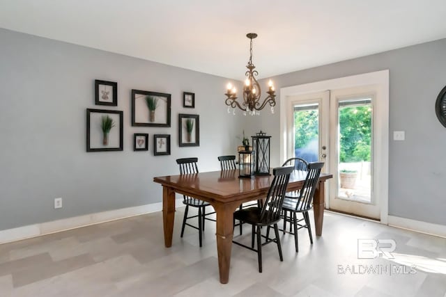 dining area with light floors, a notable chandelier, and baseboards