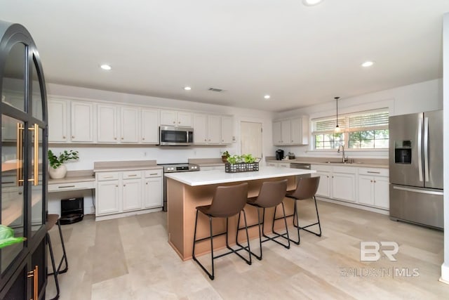 kitchen featuring a kitchen breakfast bar, a sink, visible vents, stainless steel appliances, and a kitchen island