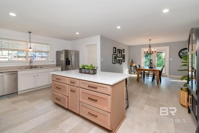 kitchen featuring a healthy amount of sunlight, a chandelier, appliances with stainless steel finishes, light countertops, and a sink