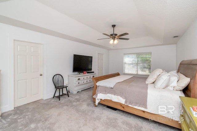 bedroom with visible vents, ceiling fan, carpet floors, and a tray ceiling