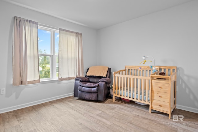 bedroom with hardwood / wood-style flooring, a nursery area, and multiple windows