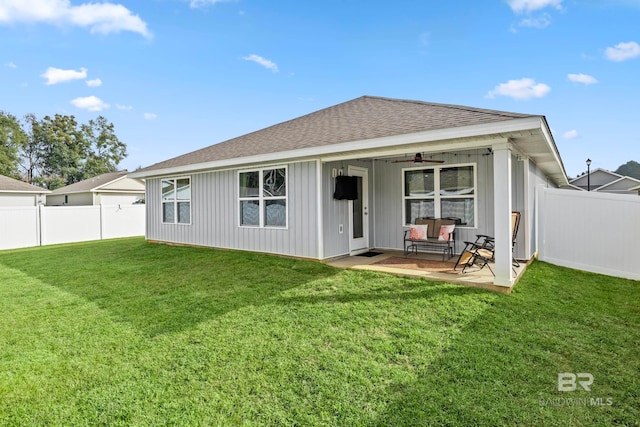 rear view of property with ceiling fan and a yard