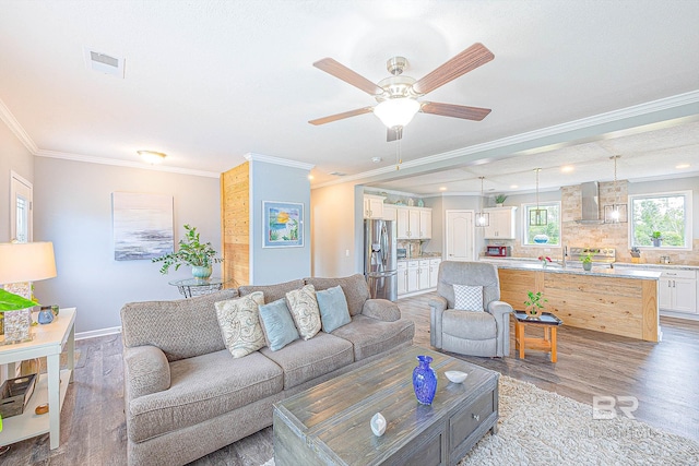 living room with ornamental molding, ceiling fan, and light hardwood / wood-style floors