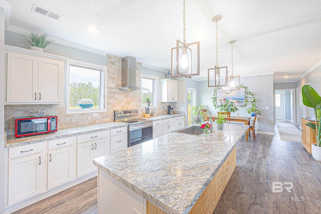 kitchen with a kitchen island with sink, electric range, sink, wall chimney range hood, and white cabinets