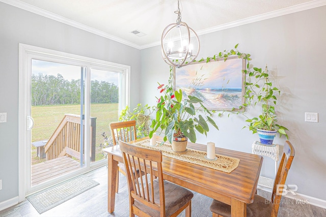 dining area featuring crown molding, a notable chandelier, and hardwood / wood-style flooring