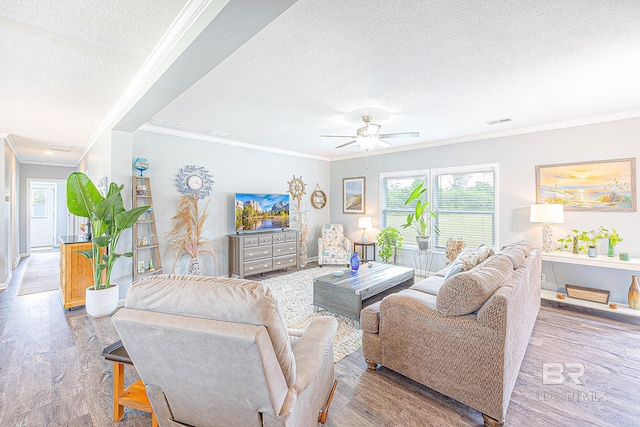 living room featuring a textured ceiling, ceiling fan, ornamental molding, and wood-type flooring