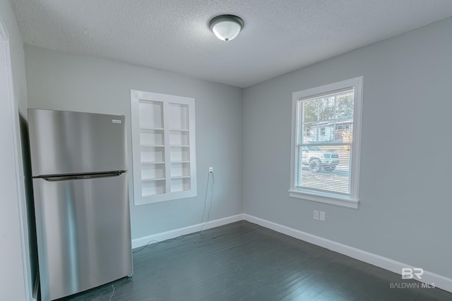 spare room with dark hardwood / wood-style flooring, built in features, and a textured ceiling