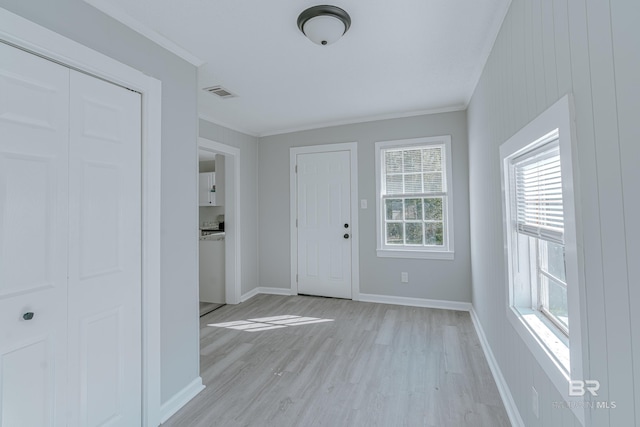 foyer entrance with crown molding and light hardwood / wood-style flooring