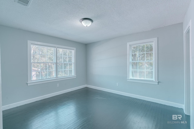 empty room featuring a textured ceiling, dark wood-type flooring, and a healthy amount of sunlight