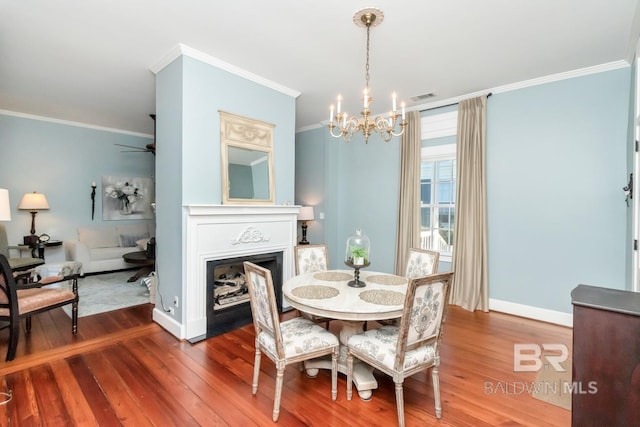 dining room featuring hardwood / wood-style floors, ceiling fan with notable chandelier, and ornamental molding