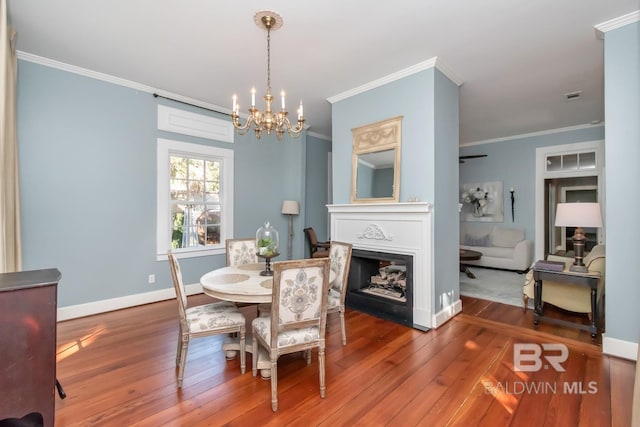 dining space featuring a chandelier, wood-type flooring, and ornamental molding